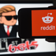 A phone showing the Reddit logo in front of a screen displaying the WallStreetBets logo.